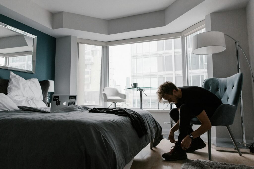 man putting on shoes in bedroom.