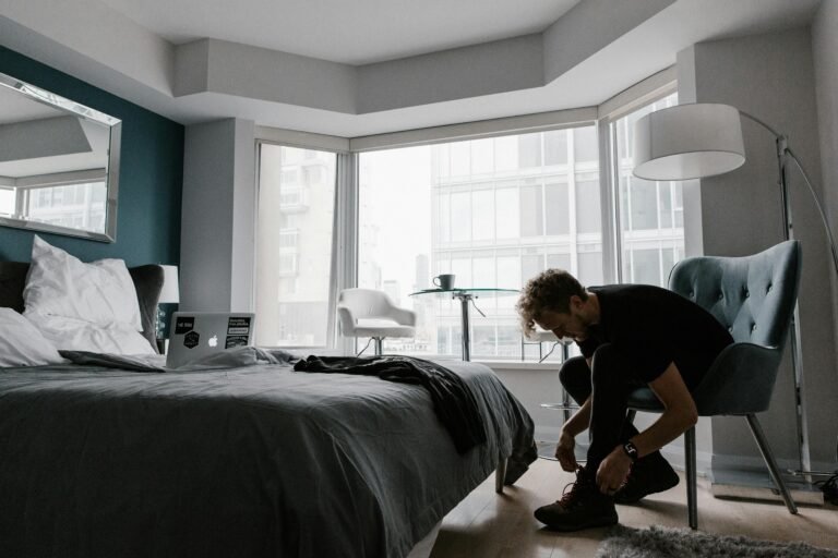 man putting on shoes in bedroom.